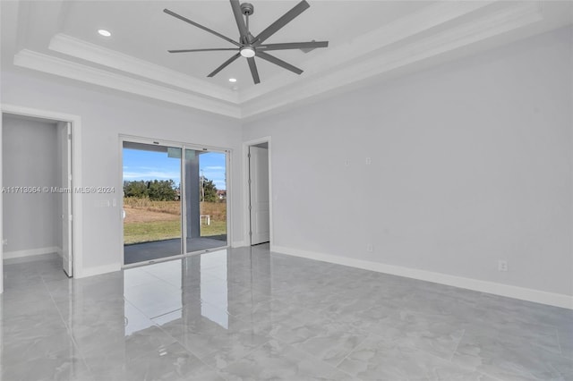 empty room featuring a tray ceiling, ceiling fan, and ornamental molding