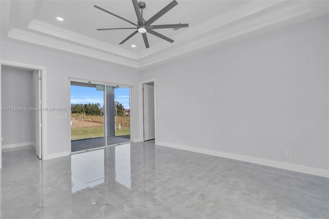 empty room featuring a tray ceiling, ornamental molding, and ceiling fan