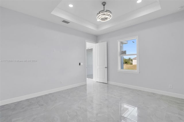 empty room featuring a tray ceiling and ornamental molding