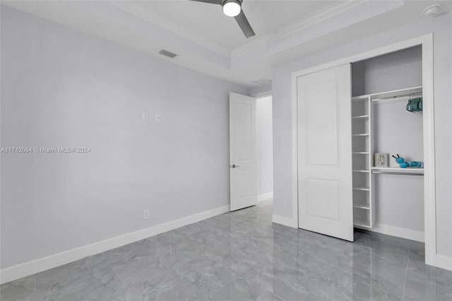 unfurnished bedroom featuring a closet, ceiling fan, ornamental molding, and a tray ceiling