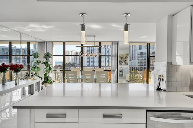 kitchen featuring decorative light fixtures, white cabinetry, backsplash, stainless steel dishwasher, and light tile patterned floors