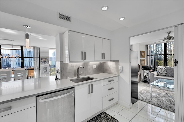 kitchen featuring sink, dishwasher, white cabinets, pendant lighting, and backsplash