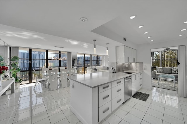 kitchen with light tile patterned floors, white cabinetry, backsplash, stainless steel dishwasher, and kitchen peninsula