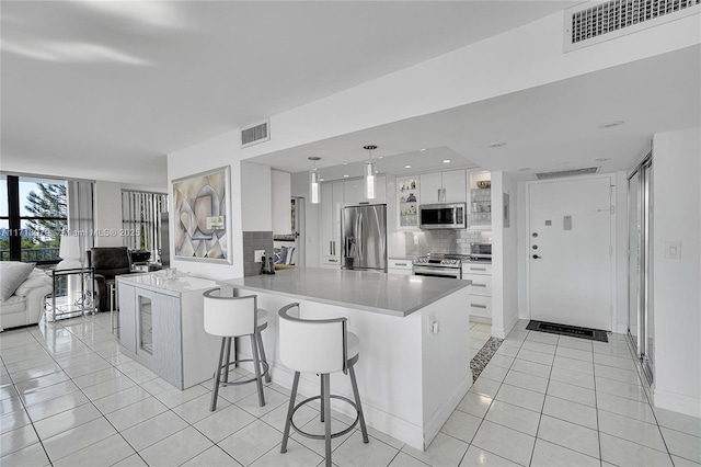 kitchen with a breakfast bar area, white cabinetry, backsplash, stainless steel appliances, and kitchen peninsula