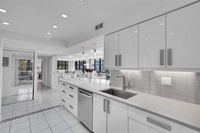 kitchen featuring white cabinetry, sink, decorative backsplash, stainless steel dishwasher, and light tile patterned floors