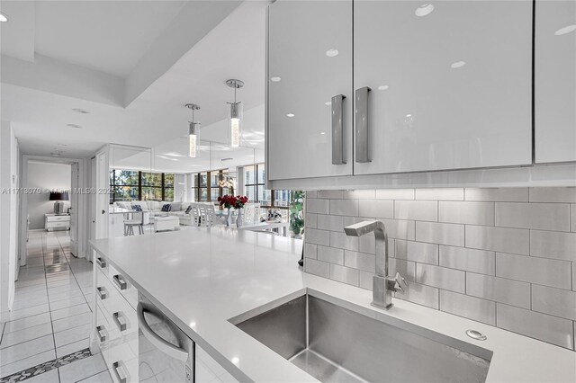 kitchen with pendant lighting, sink, dishwasher, tasteful backsplash, and white cabinets