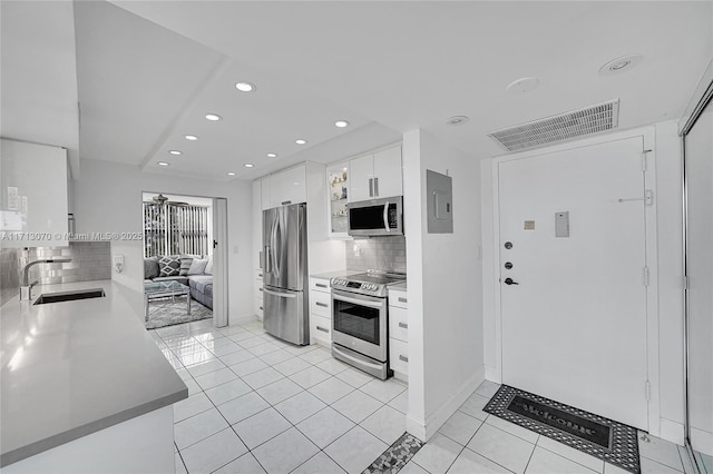 kitchen with sink, light tile patterned floors, appliances with stainless steel finishes, white cabinets, and decorative backsplash