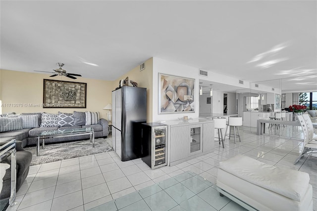 kitchen featuring light tile patterned flooring, fridge, a kitchen breakfast bar, ceiling fan, and beverage cooler