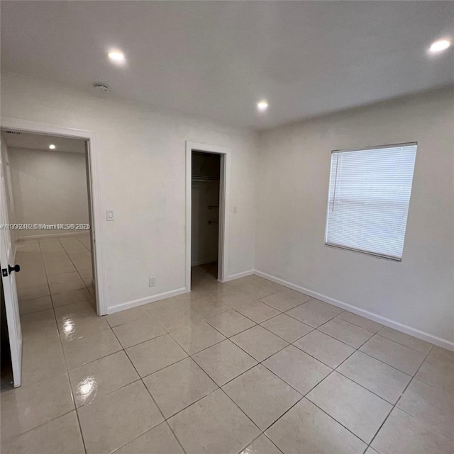 unfurnished bedroom featuring light tile patterned floors, a walk in closet, and a closet