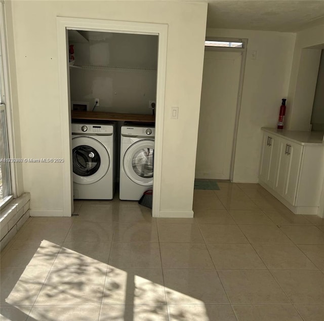laundry room with light tile patterned floors, baseboards, and washer and clothes dryer