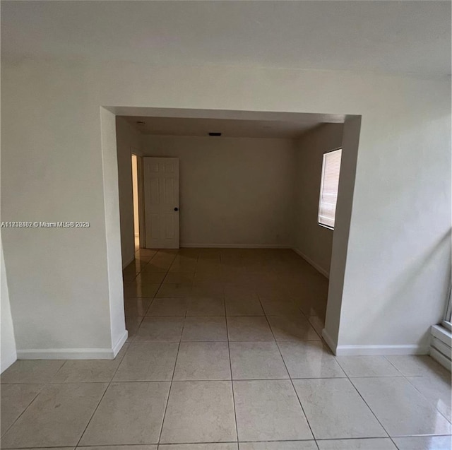 corridor with baseboards and light tile patterned floors