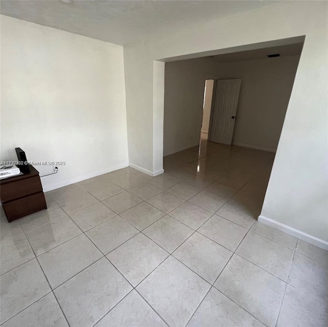 unfurnished room featuring baseboards and light tile patterned floors