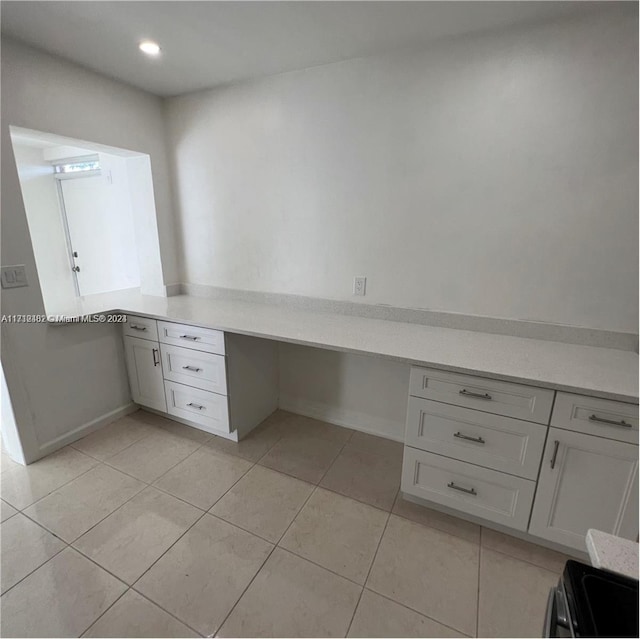 unfurnished office featuring light tile patterned flooring and built in desk