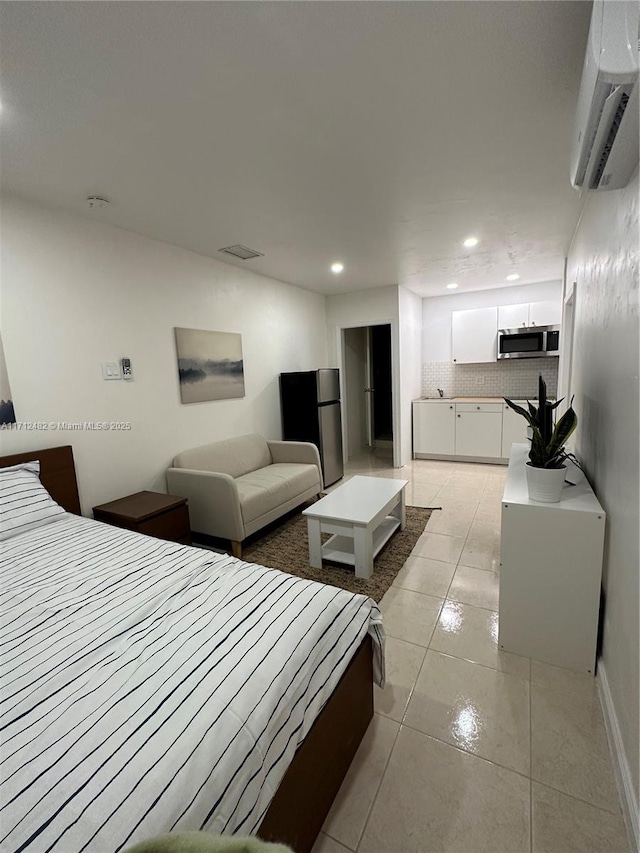 bedroom with stainless steel fridge, a wall unit AC, and light tile patterned floors