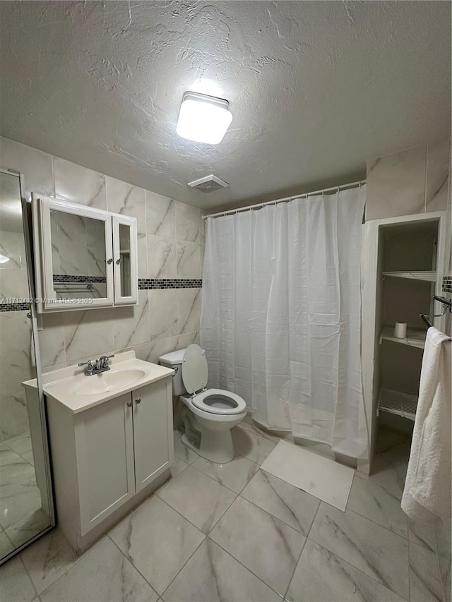 bathroom with vanity, curtained shower, a textured ceiling, and toilet