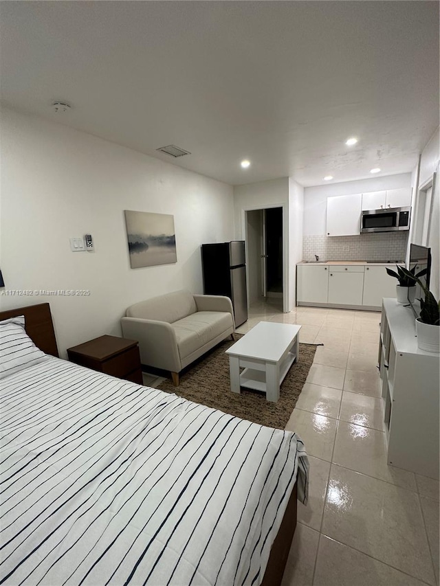 bedroom with light tile patterned floors and stainless steel fridge