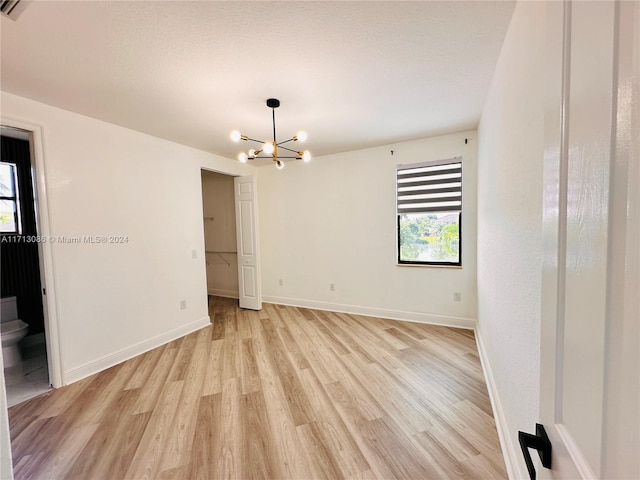 spare room featuring a chandelier and light wood-type flooring