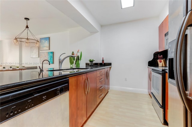 kitchen featuring appliances with stainless steel finishes, light wood-type flooring, sink, decorative light fixtures, and an inviting chandelier