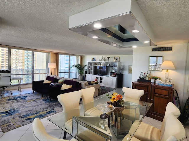 dining area with a raised ceiling, light tile patterned floors, and a textured ceiling