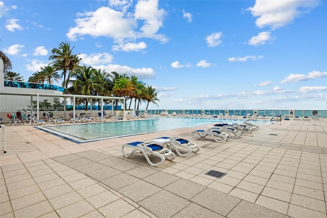 view of pool with a water view and a patio