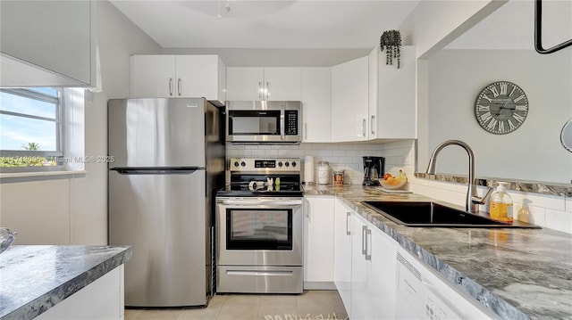 kitchen with backsplash, sink, appliances with stainless steel finishes, light tile patterned flooring, and white cabinetry