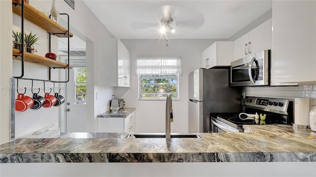 kitchen featuring appliances with stainless steel finishes, backsplash, ceiling fan, sink, and white cabinets