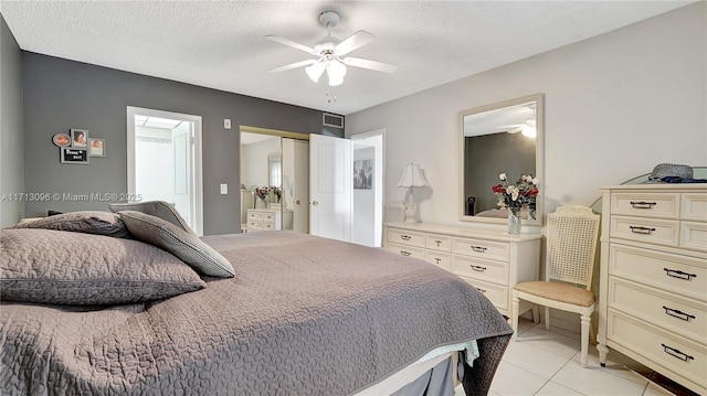 bedroom featuring ceiling fan, a closet, light tile patterned floors, and a textured ceiling