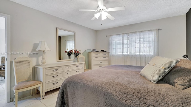 bedroom with ceiling fan, light tile patterned floors, and a textured ceiling