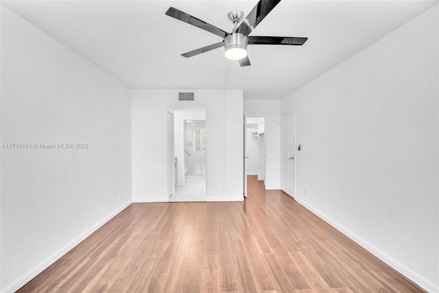 unfurnished bedroom featuring ceiling fan, a walk in closet, ensuite bath, and light hardwood / wood-style flooring