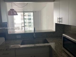 kitchen with white cabinets, sink, and dark stone counters