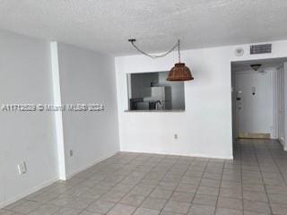 tiled empty room with a textured ceiling