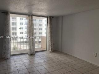 tiled empty room featuring a textured ceiling