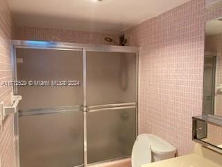 bathroom featuring vanity, tile walls, and toilet