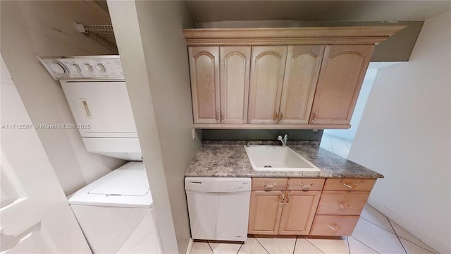 clothes washing area with light tile patterned floors, stacked washer and clothes dryer, and sink