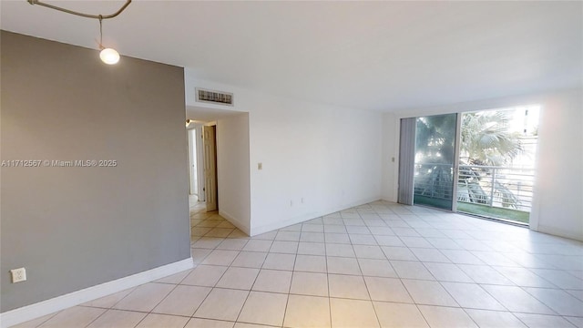 unfurnished room featuring a wall of windows, light tile patterned flooring, visible vents, and baseboards