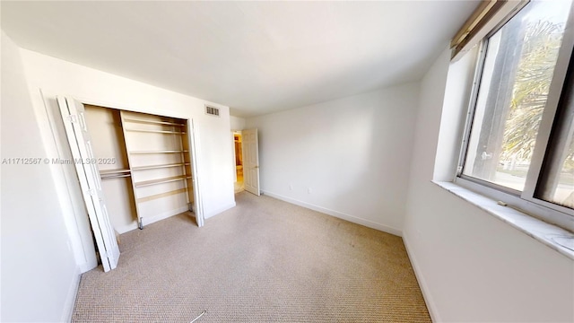 unfurnished bedroom featuring light carpet and a closet