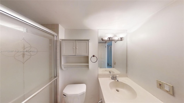 bathroom with vanity, toilet, and a shower with shower door