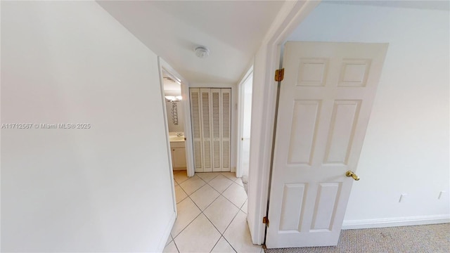 corridor featuring baseboards and light tile patterned flooring