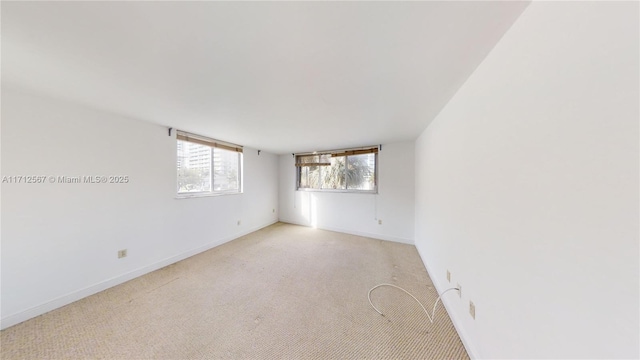 spare room with light carpet and baseboards