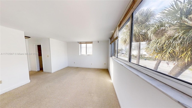 unfurnished room with light carpet and baseboards