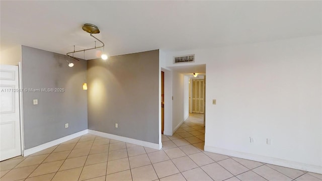 empty room featuring light tile patterned flooring and track lighting