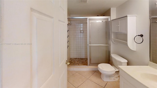 bathroom featuring toilet, vanity, tile patterned floors, and a shower with door