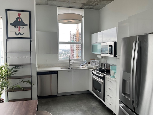 kitchen with a sink, appliances with stainless steel finishes, light countertops, and white cabinetry