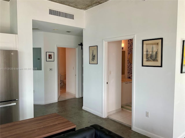 corridor with electric panel, visible vents, a high ceiling, and baseboards