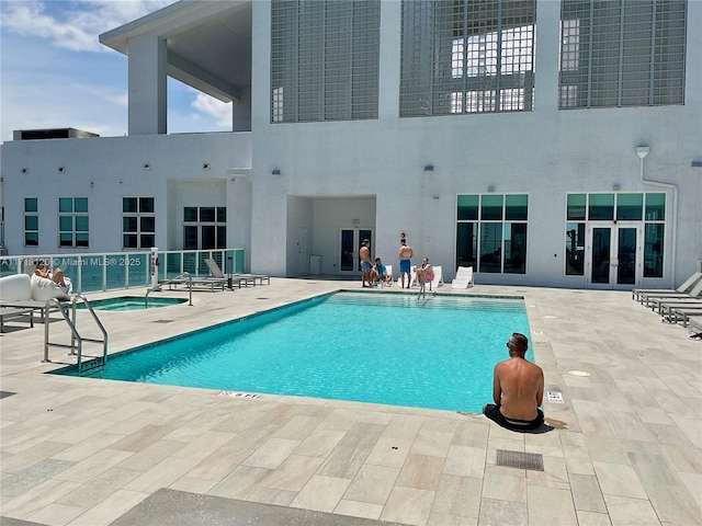 community pool with a hot tub and a patio area