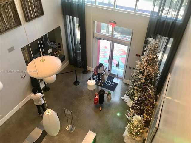 living room featuring finished concrete flooring, french doors, baseboards, and a towering ceiling