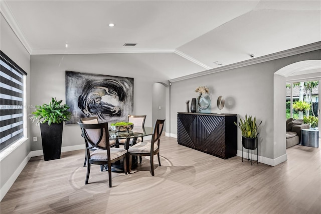 dining space featuring light wood-type flooring, lofted ceiling, and ornamental molding