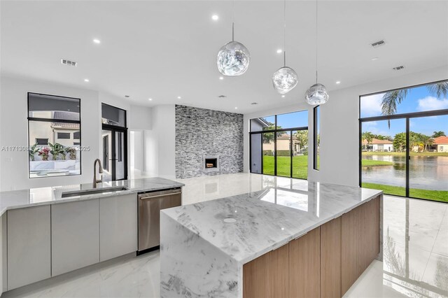 kitchen featuring gray cabinetry, stainless steel appliances, wall chimney range hood, pendant lighting, and a center island