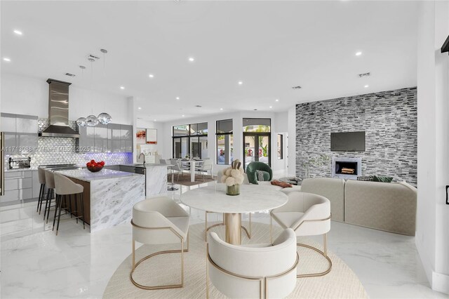 kitchen with backsplash, pendant lighting, wall chimney range hood, and stainless steel appliances