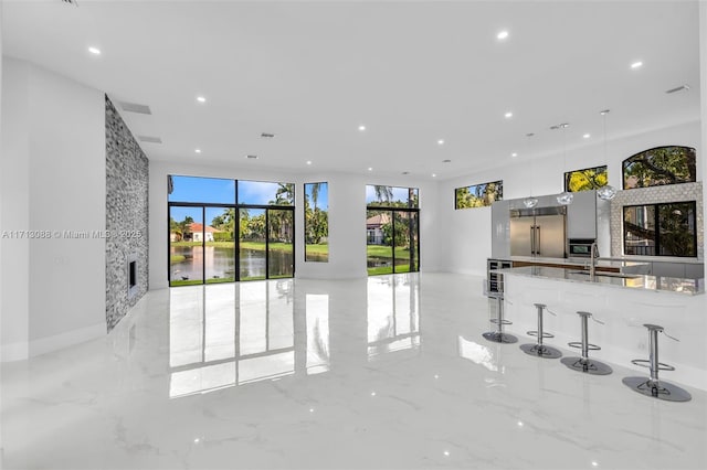 unfurnished living room with marble finish floor, beverage cooler, recessed lighting, and a sink